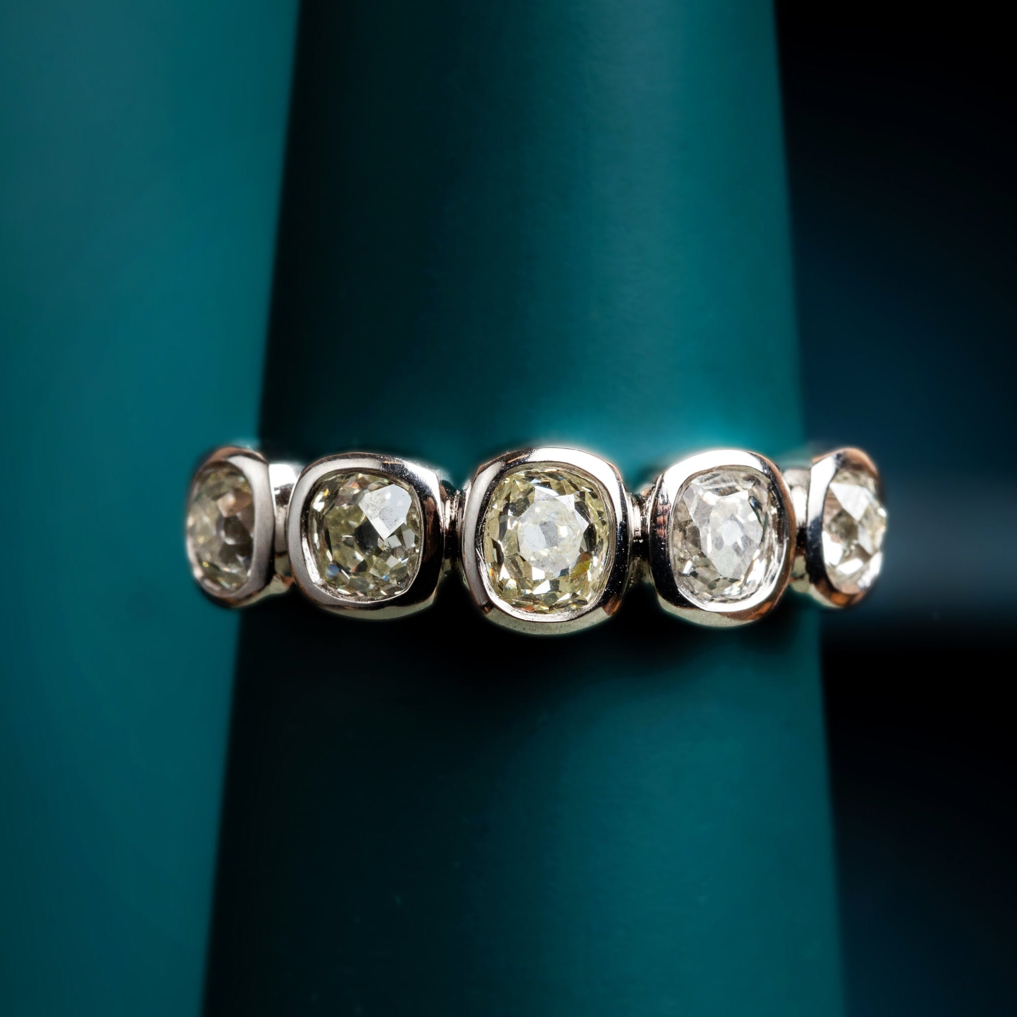 Old cut diamond cobblestone set ring in platinum on a dark green background