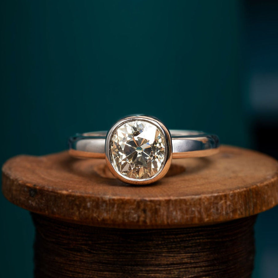 Old Cut Solitaire cobblestone set Diamond ring on a wooden spool with a dark background