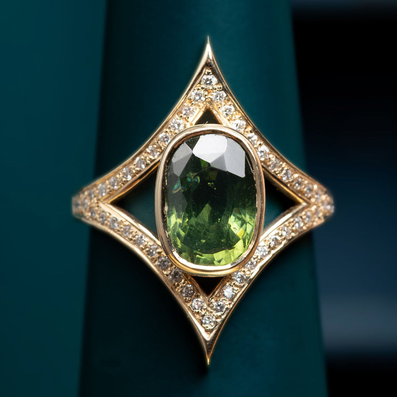One of a kind gold ring with a green zircon and diamonds on a dark green stand