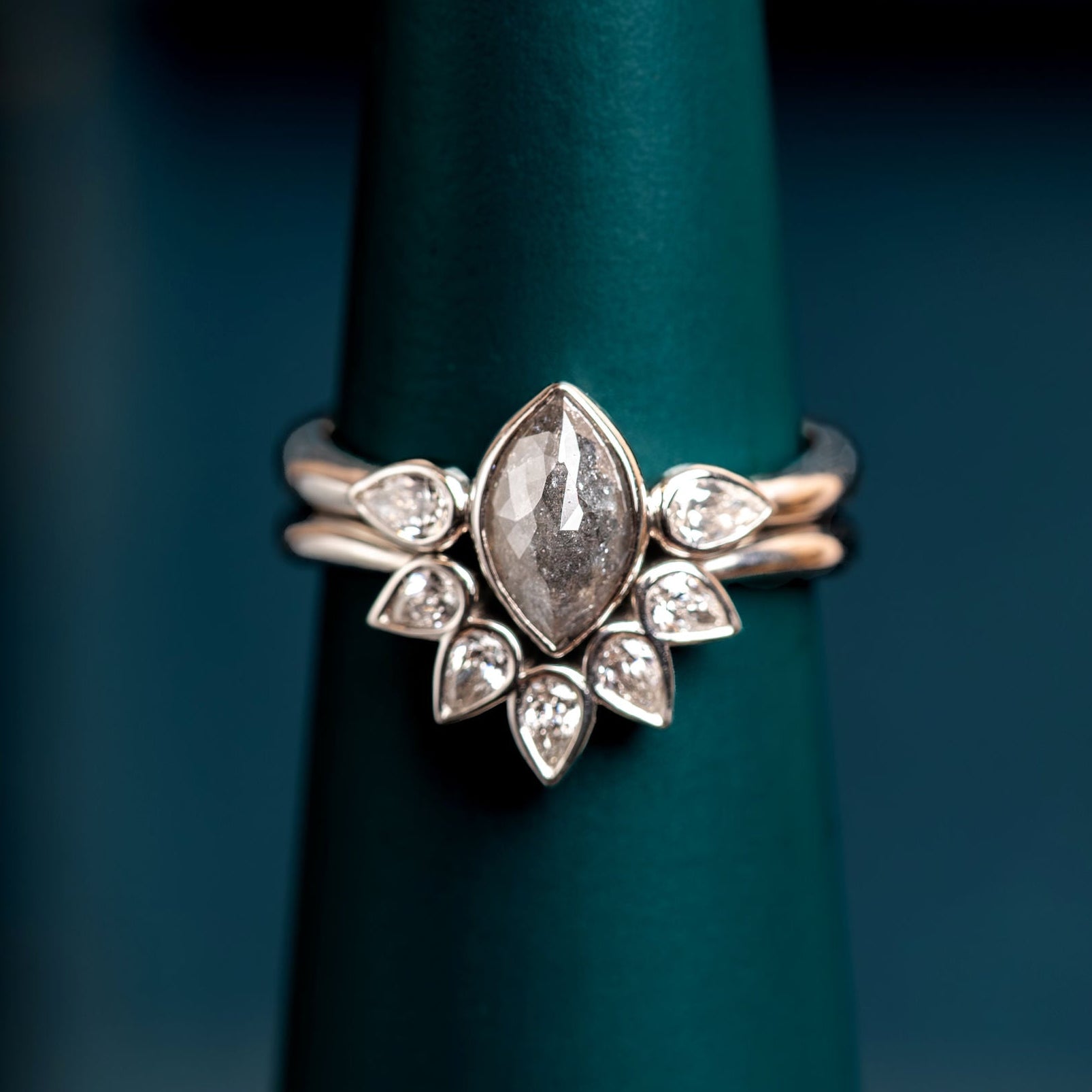 White Gold Platinum ring set with a central salt and pepper diamond on a dark green stand. Engagement ring with tiara wedding ring